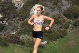 Alexandra Blake runs along a rocky path near the ocean.