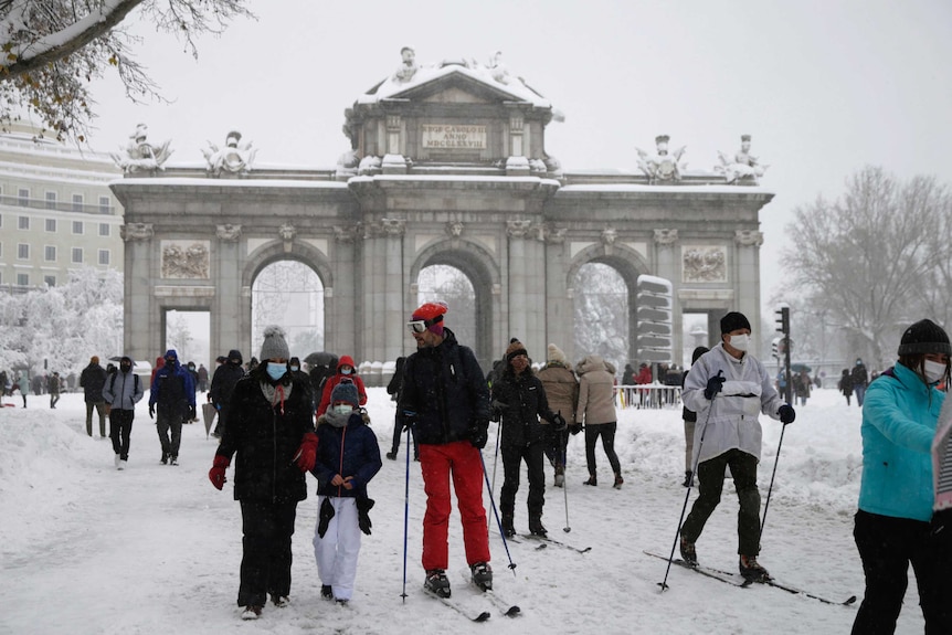 People ski past La Puerta de Alcala during a heavy snowfall in downtown Madrid.