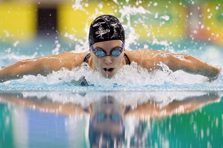 Woman in the pool doing butterfly.