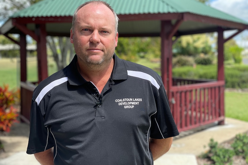 A man in a black shirt stands with a gazebo in the background. 