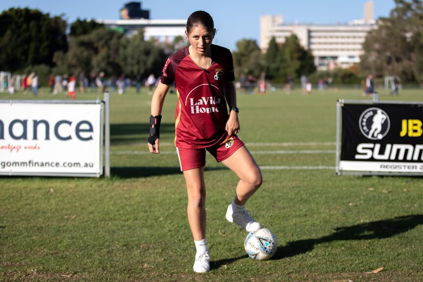 Subiaco AFC player Halla Harding stands over a soccer ball wearing her playing uniform on a soccer pitch.