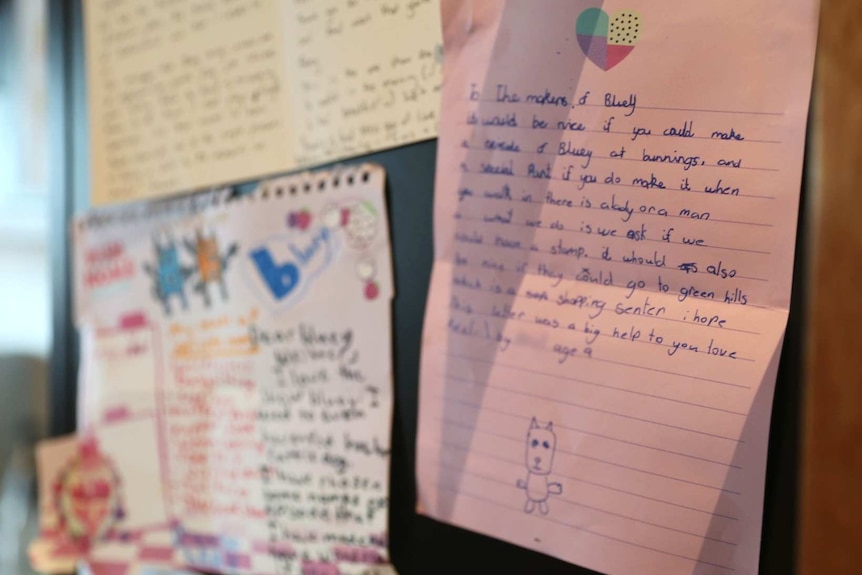 Letters written by children to the makers of Bluey stuck on a cupboard.