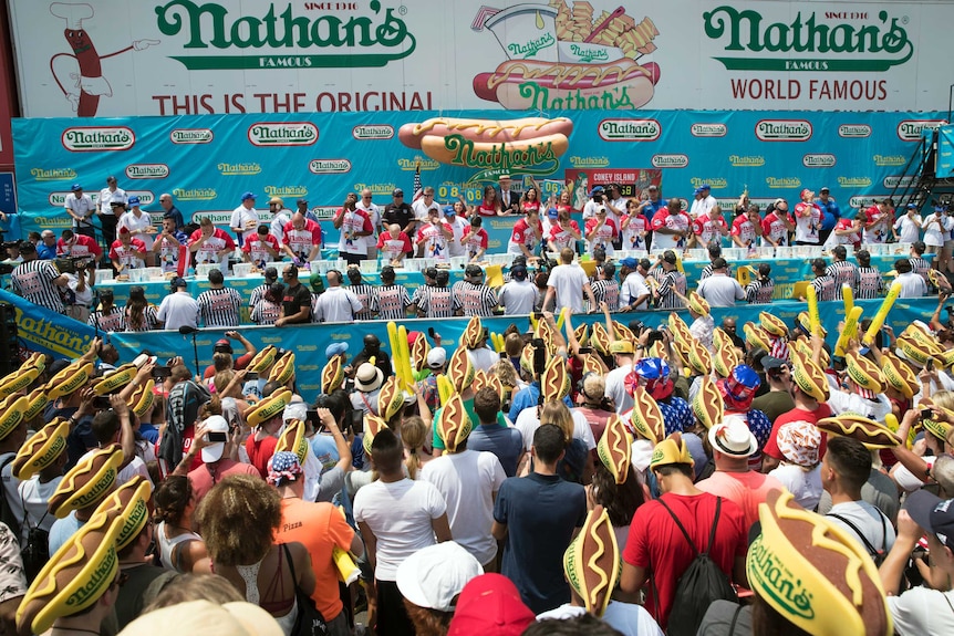 Fans wearing hot dog hats watch the male contestants