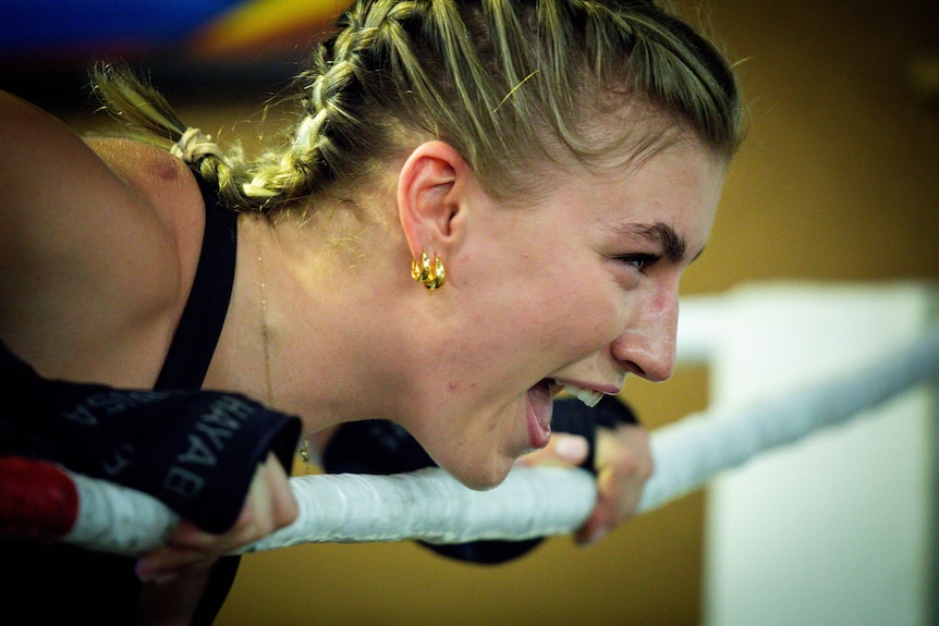 Boxer Marissa Williamson-Pohlman, leaning over the ring ropes, laughing at the gym