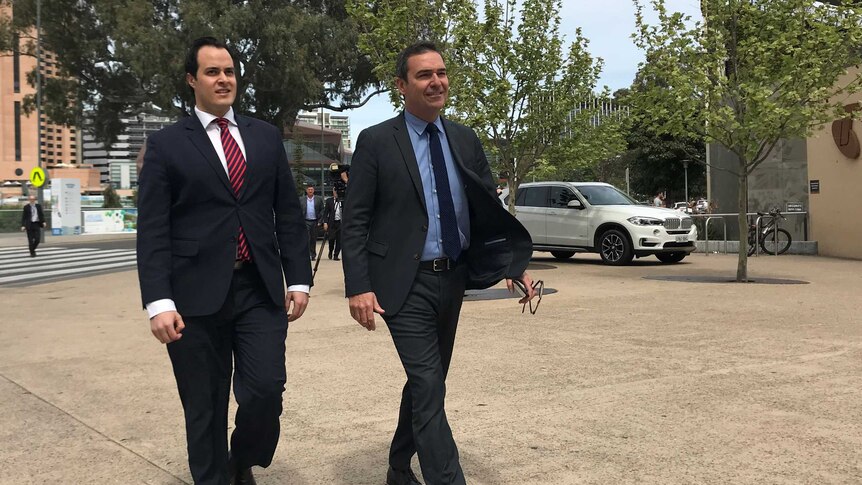 Two men in suits walk towards the camera