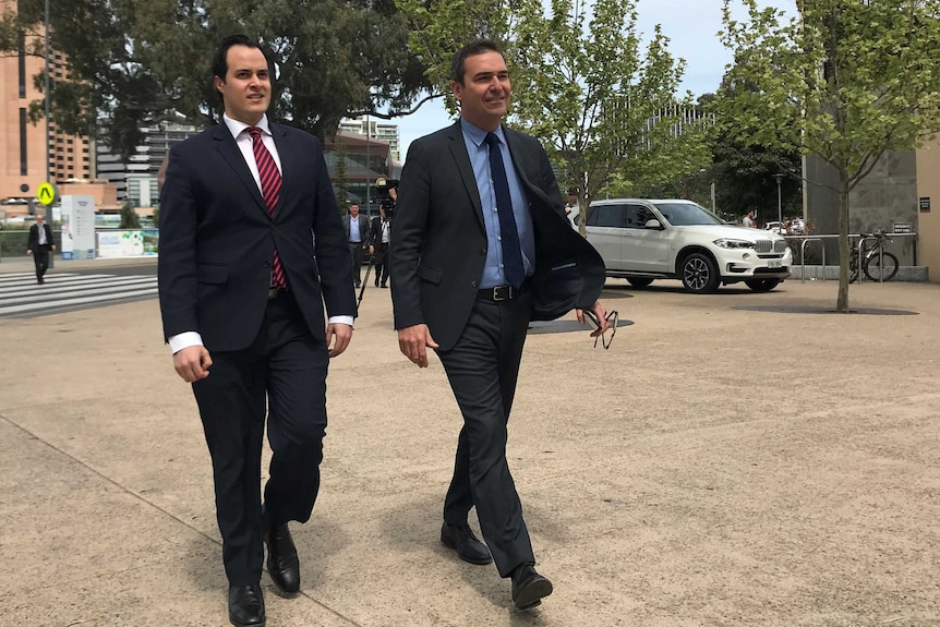 Two men in suits walk towards the camera