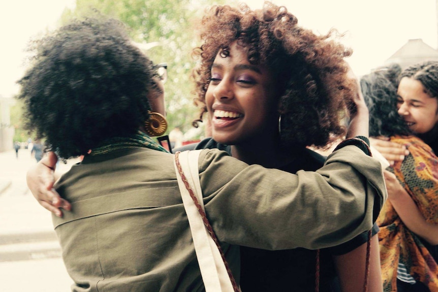 Two young African women embracing and smiling