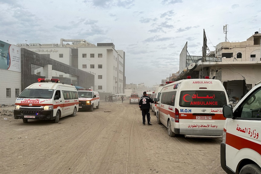Ambulances parked on either side of a dirt road surrounded by buildings.