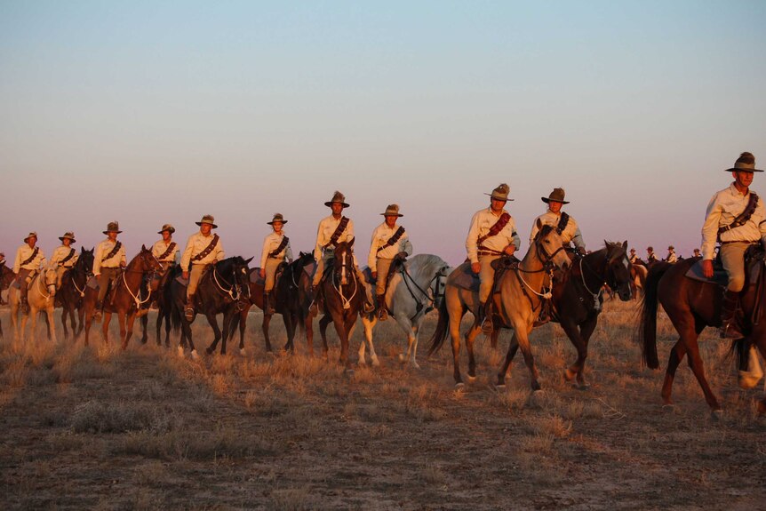 Men and women on horseback at the sun sets.