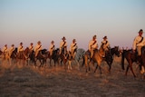A column of uniformed horsemen and women ride in the outback as part of a Beersheeba re-enactment.
