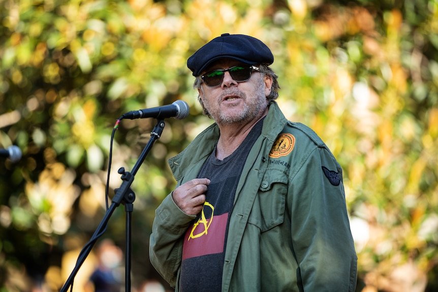 A man in sunglasses speaking into a microphone.