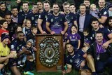 Players, family and officials of the Storm celebrate around the minor premiership shield in September, 2016.