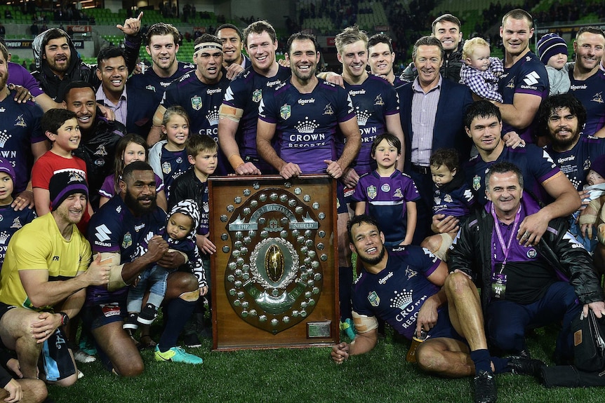 Players, family and officials of the Storm celebrate around the minor premiership shield in September, 2016.