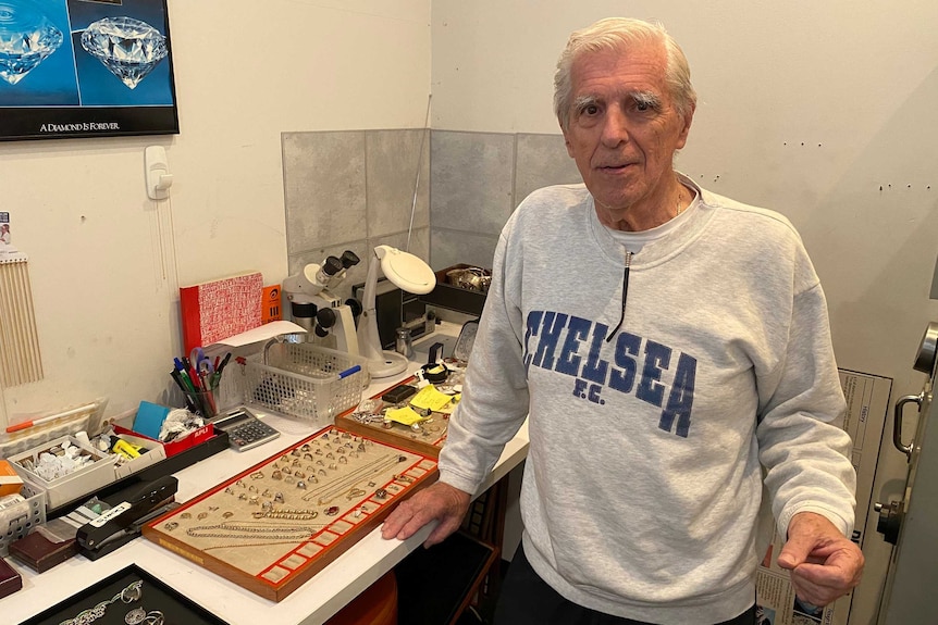 A man with white hair and wearing a grey jumper with the words Chelsea FC on the front