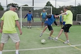 Group of men over 55 play walking football enthusiastically.