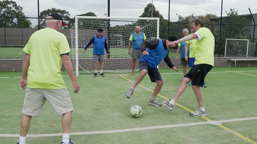 Group of men over 55 play walking football enthusiastically.