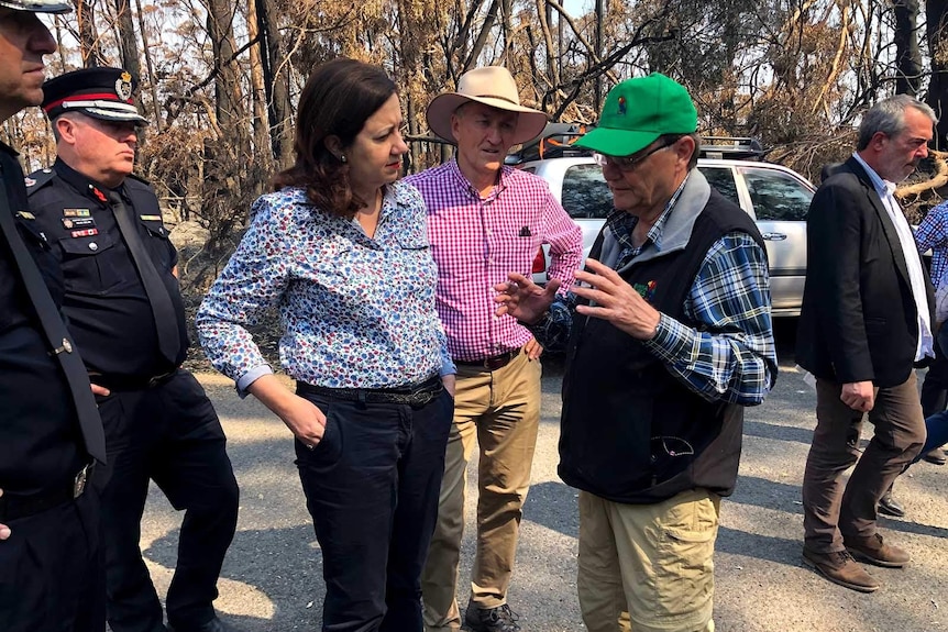 Queensland Premier Annastacia Palaszczuk speaking with a man in front of burnt-out bushland
