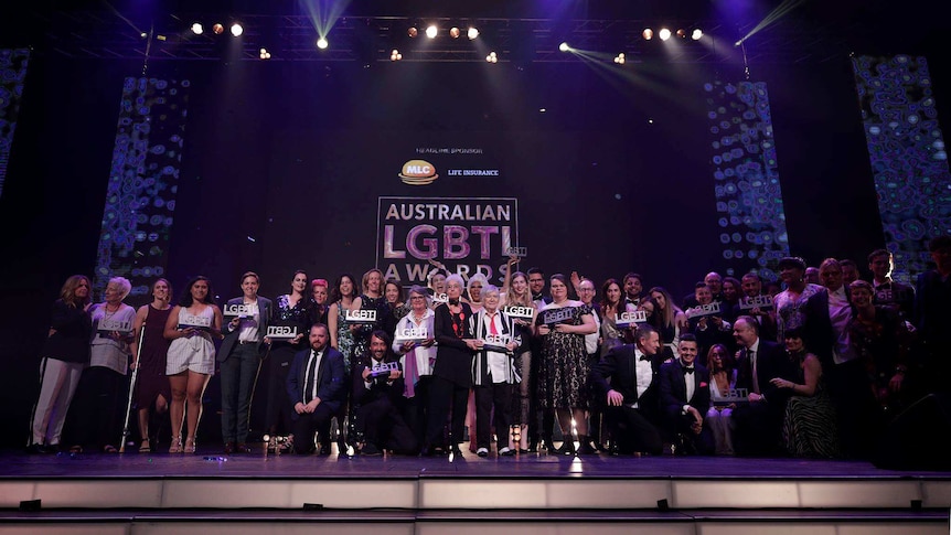 People on a stage holding trophies made to look like the letters LGBTI
