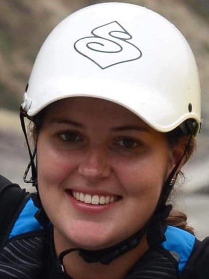 A young woman wearing a white helmet smiles into the camera