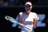 Tennis player Maria Sharapova stands on court with a big smile, clenching her fist in victory after a match in Melbourne.