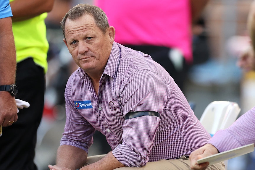 A man sits on the sidelines as he coaches the Broncos 