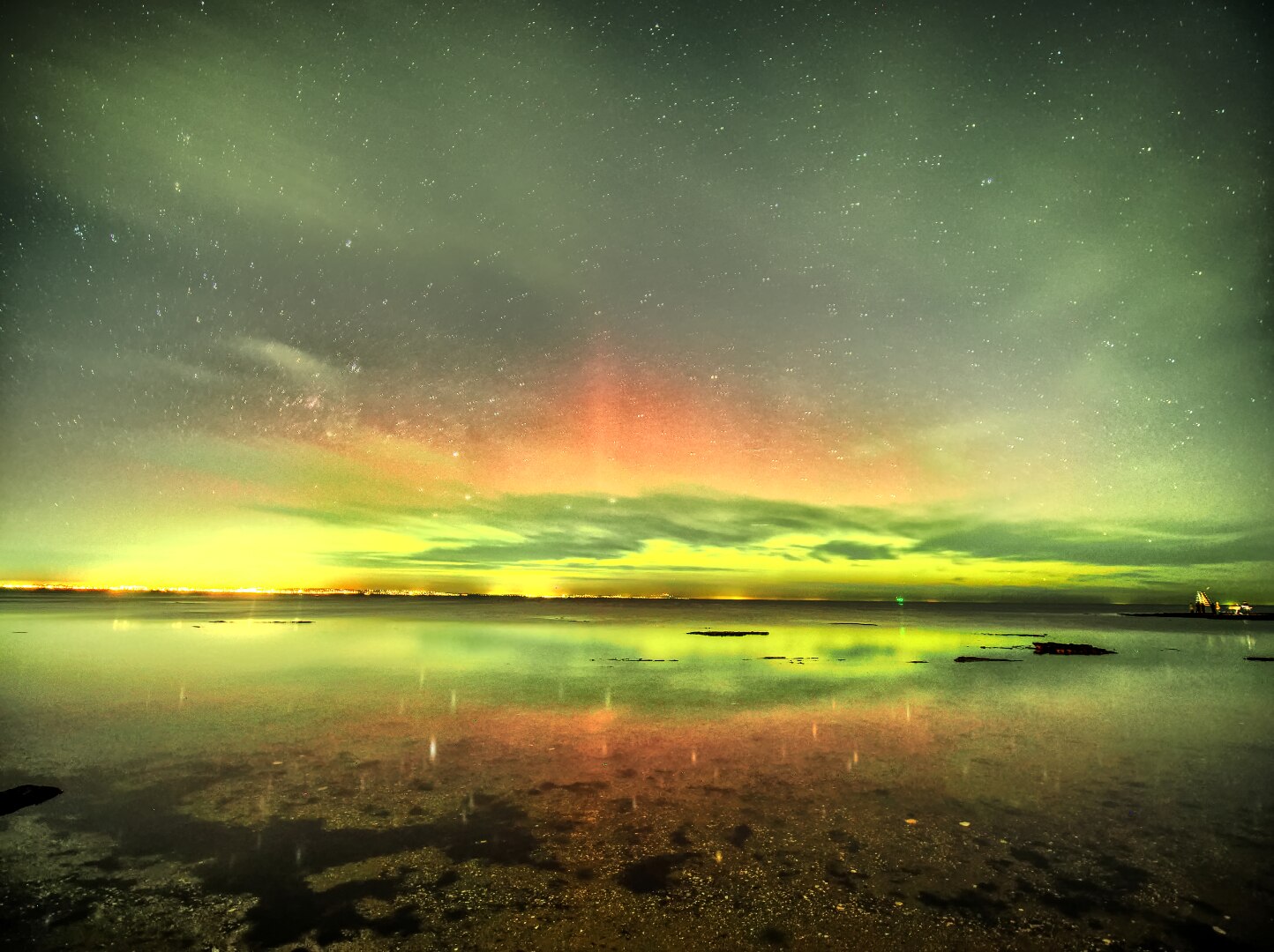 Um céu verde com vista para uma praia à noite