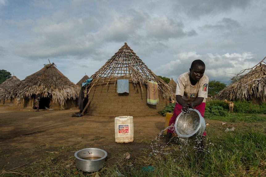 A woman carries a bucket outside her home in Kudo village, South Sudan.