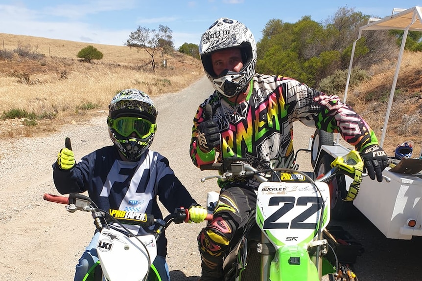A boy and a man posing on dirt bikes