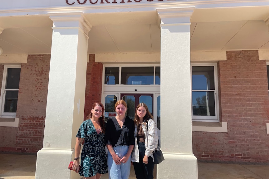 Three women stand in front of doorway with Geraldton Courthouse sign above