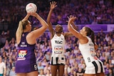 A Queensland Firebirds goal shooter gets ready to take a shot in Super Netball as Magpies defenders try to block.