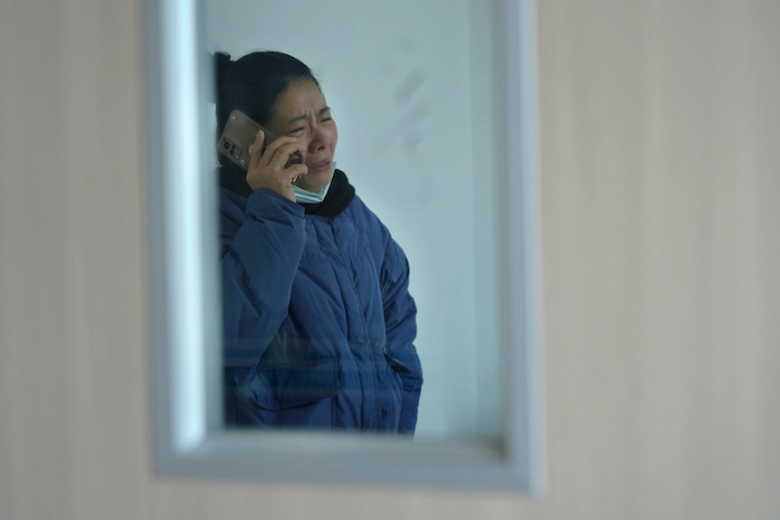A relative of injured people cries as she talks to a phone at a hospital in China.