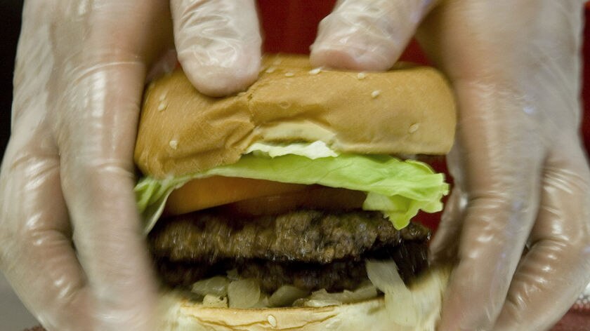 A fast food employee makes a hamburger