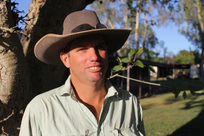 a man in a hat with trees behind.