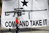 A demonstrator helps hold a large "Come and Take It" banner.