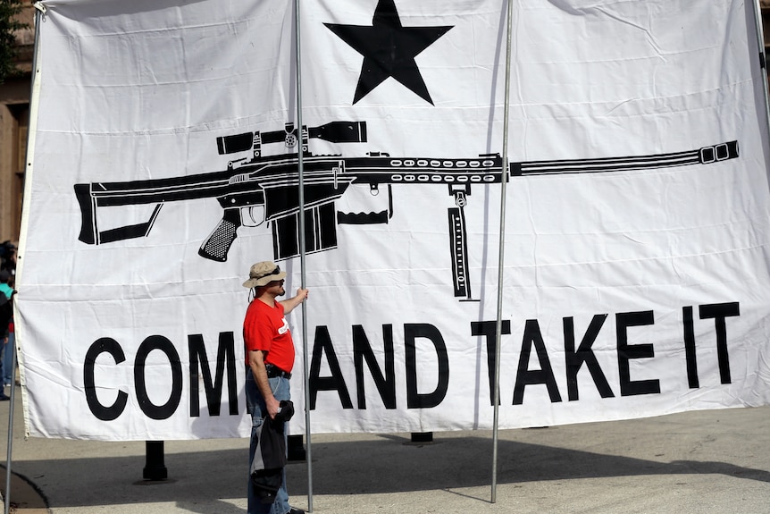 A demonstrator helps hold a large "Come and Take It" banner.