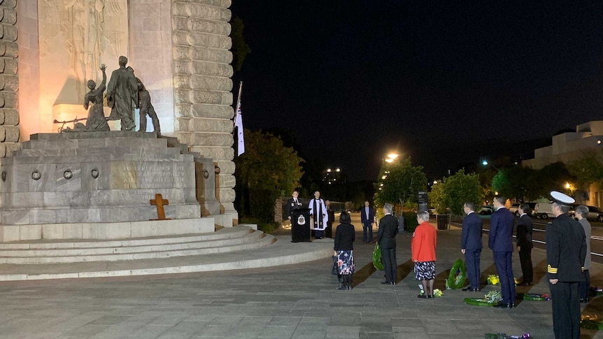 people lined up in front of a memorial with a lectern set up to the side