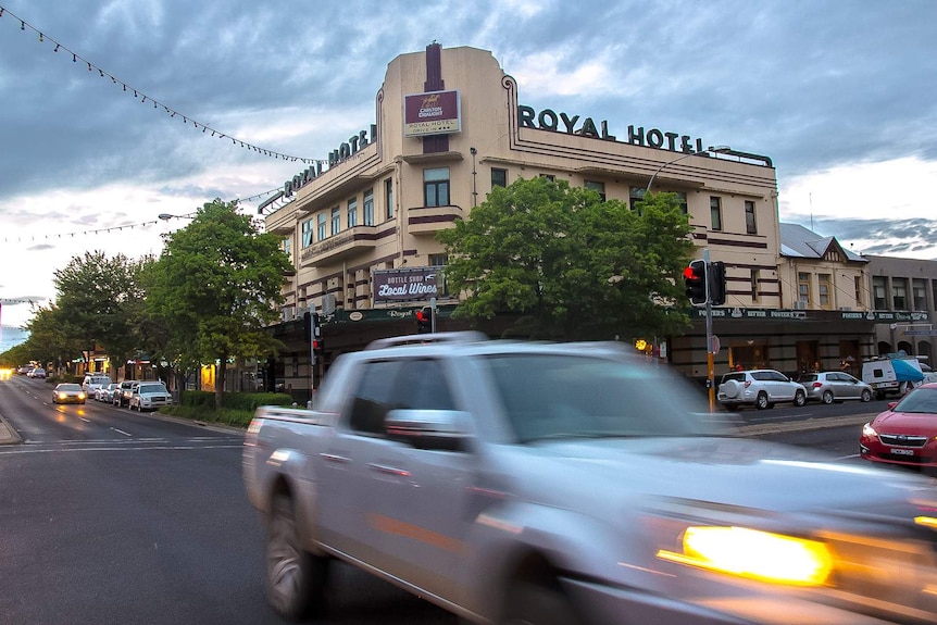 Wide shot of an historic pub with the words Royal Hotel on the top of the building with traffic in front
