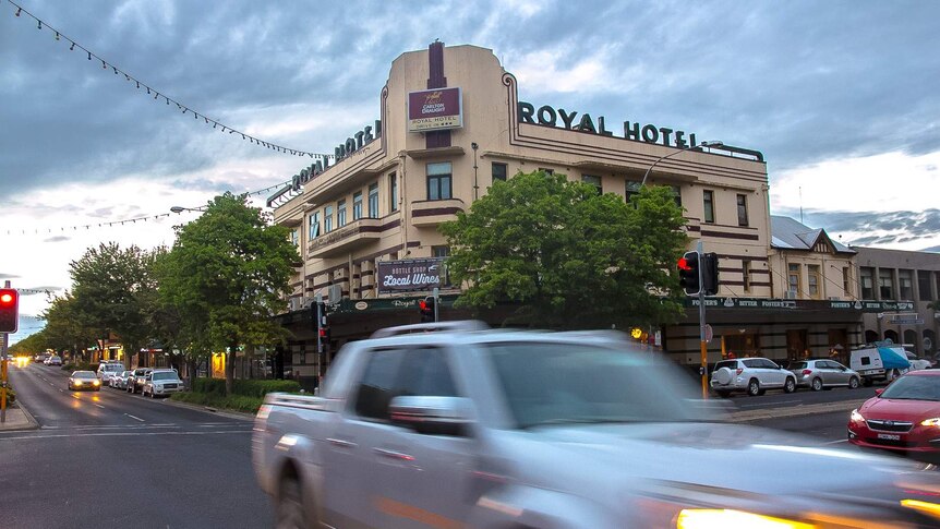 Wide shot of an historic pub with the words Royal Hotel on the top of the building with traffic in front