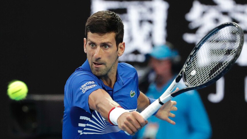 Novak Djokovic eyes the ball as he hits a backhand at the Australian Open.