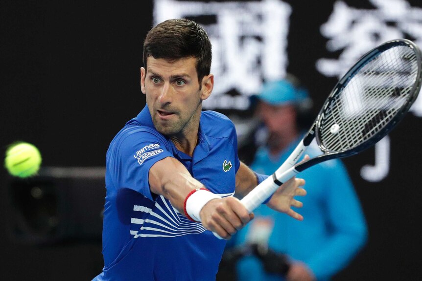 Novak Djokovic eyes the ball as he hits a backhand at the Australian Open.