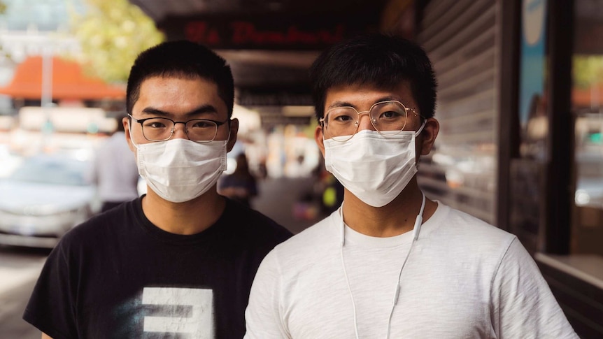Two men wearing face masks in Perth stand on a street.