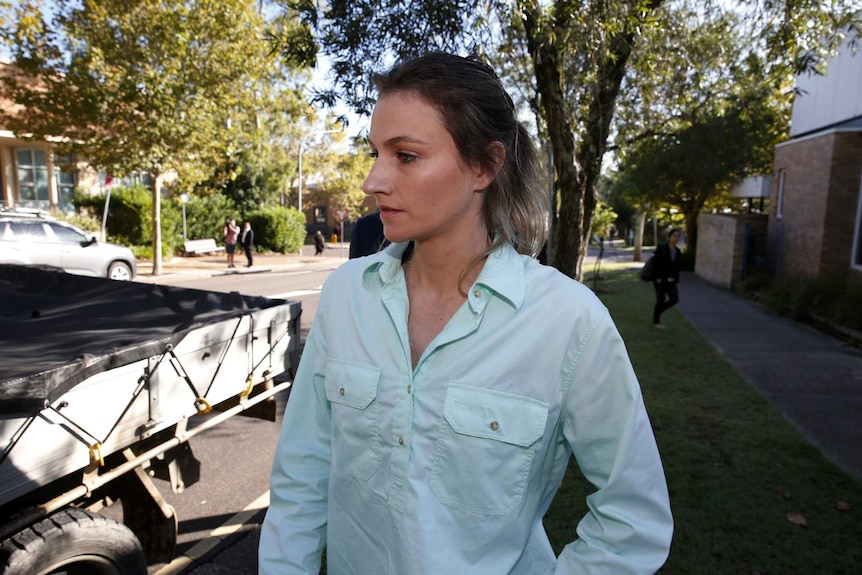 A woman looks away from the camera while walking down the street.