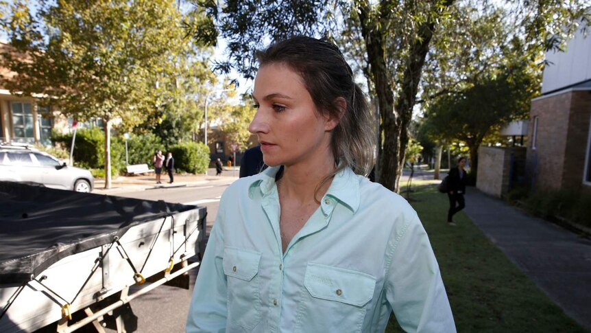 A woman looks away from the camera while walking down the street.