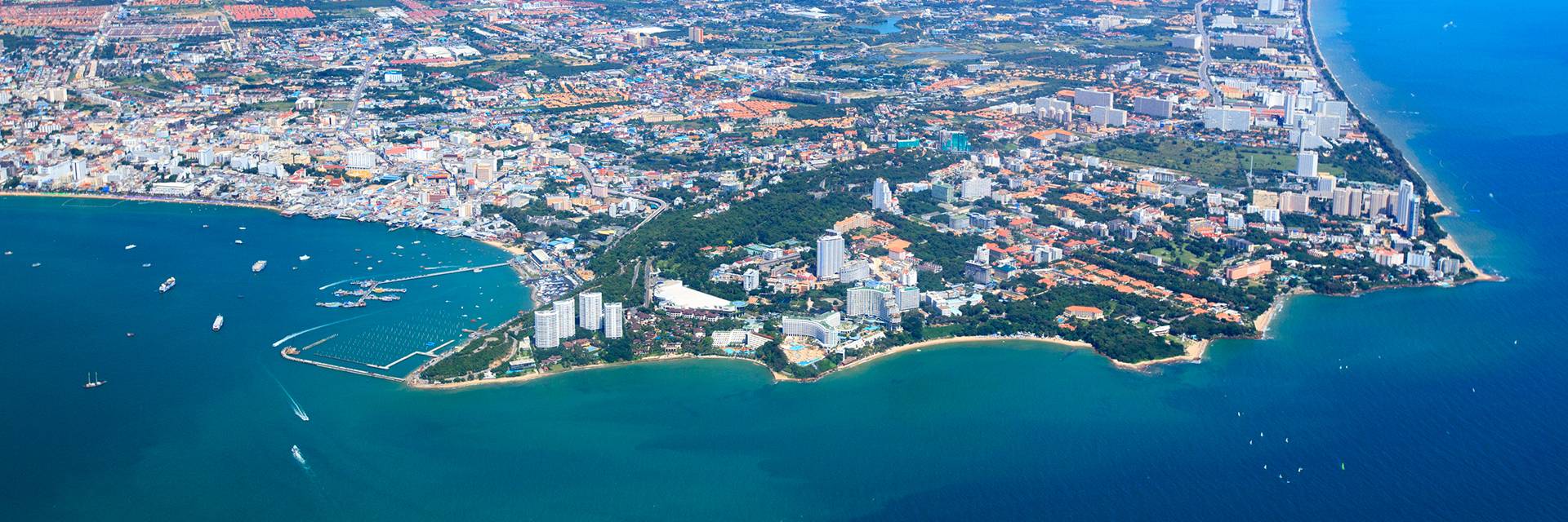 A drone shot showing a crystal blue coastline and a sprawling city 