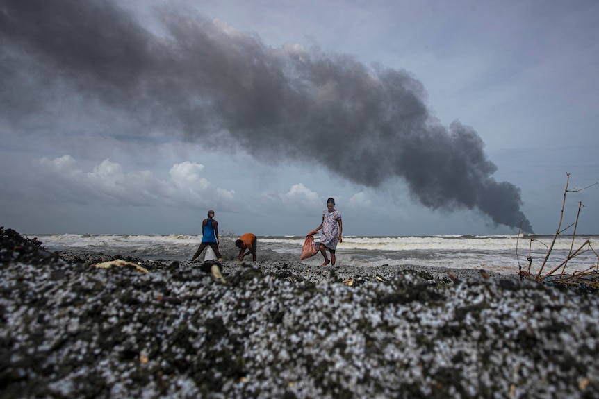 People salvage wreckage washed to the shore from the burning ship