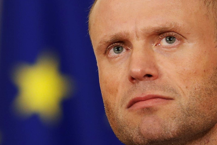 Maltese Prime Minister Joseph Muscat is shown close up in with the EU flag seen faintly behind him.