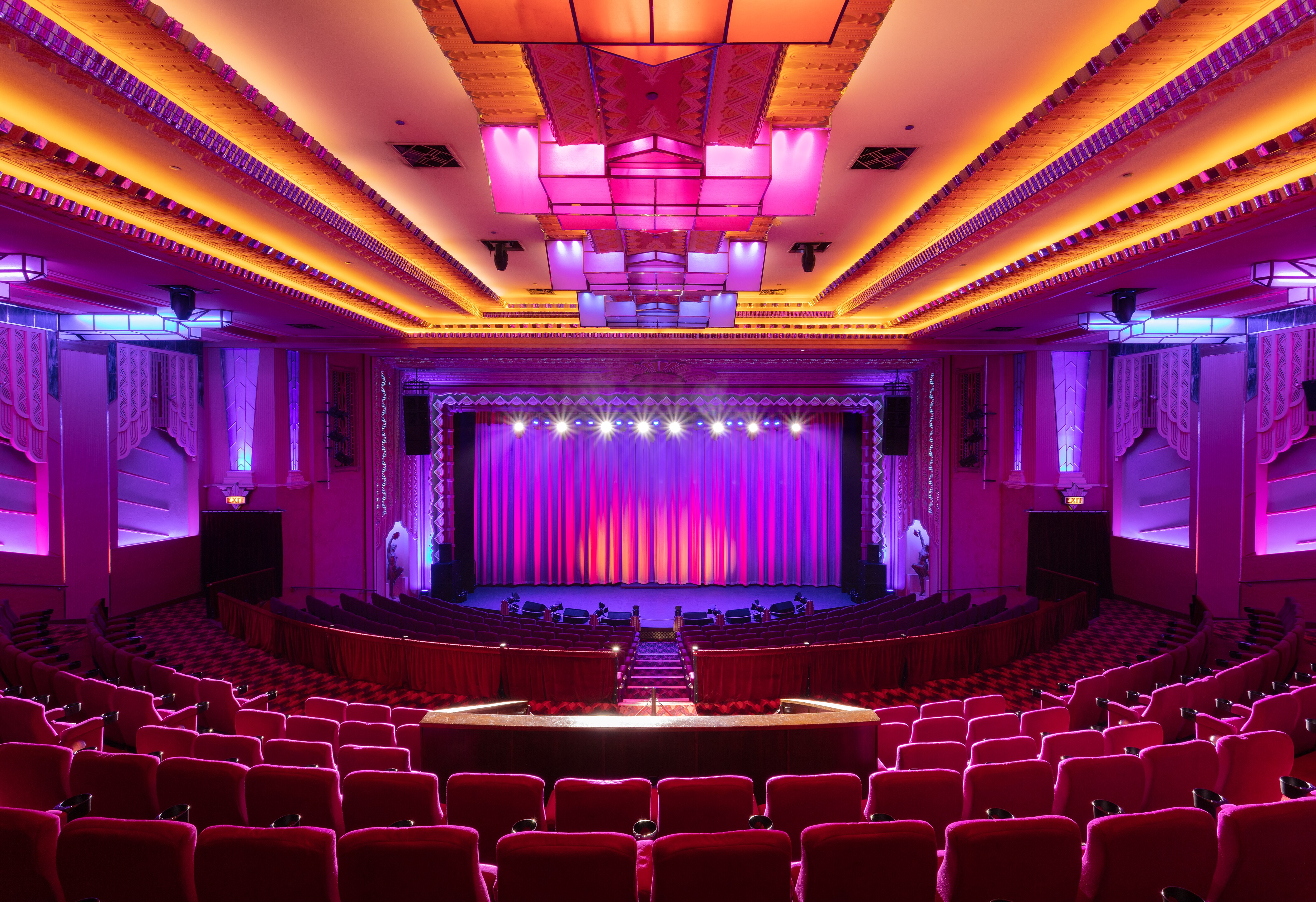 Una imagen bonita de un auditorio en el Hayden Orpheum en Cremorne, con mucha iluminación rosa y púrpura suave.