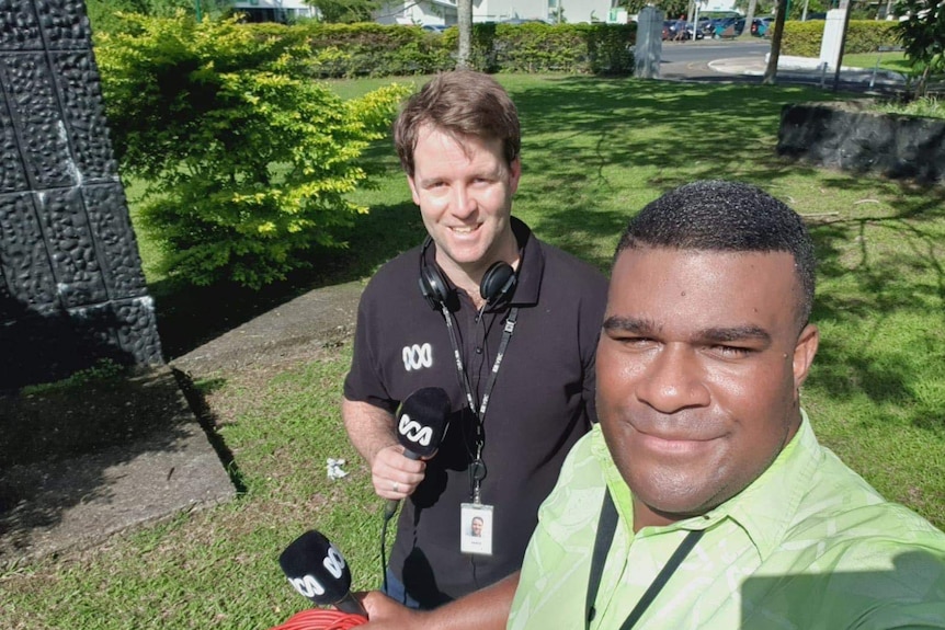 ABC reporter Fred Hooper standing outside in the sun with FBC's reporter Josaia Nanuqa