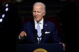 President Joe Biden stands at a lectern wearing a suit.  