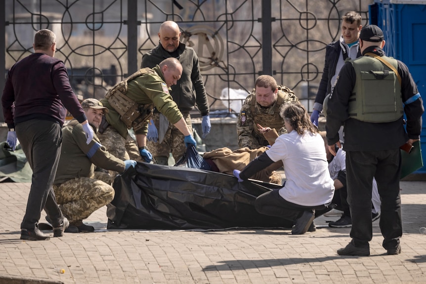 Ukrainian soldiers clear out bodies after a rocket attack